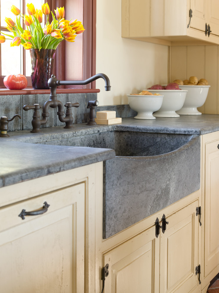 Example of a mid-sized country single-wall brick floor and red floor eat-in kitchen design in Philadelphia with a farmhouse sink, raised-panel cabinets, beige cabinets, concrete countertops, paneled appliances, an island and gray countertops