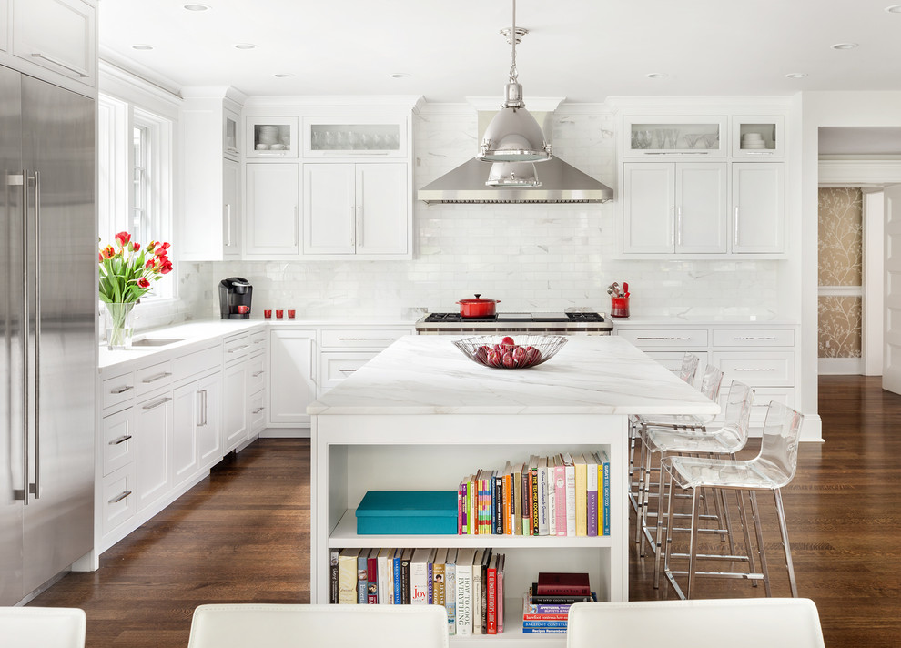 Classic l-shaped kitchen/diner in New York with a submerged sink, shaker cabinets, white cabinets, white splashback, marble splashback, stainless steel appliances, dark hardwood flooring, an island and brown floors.