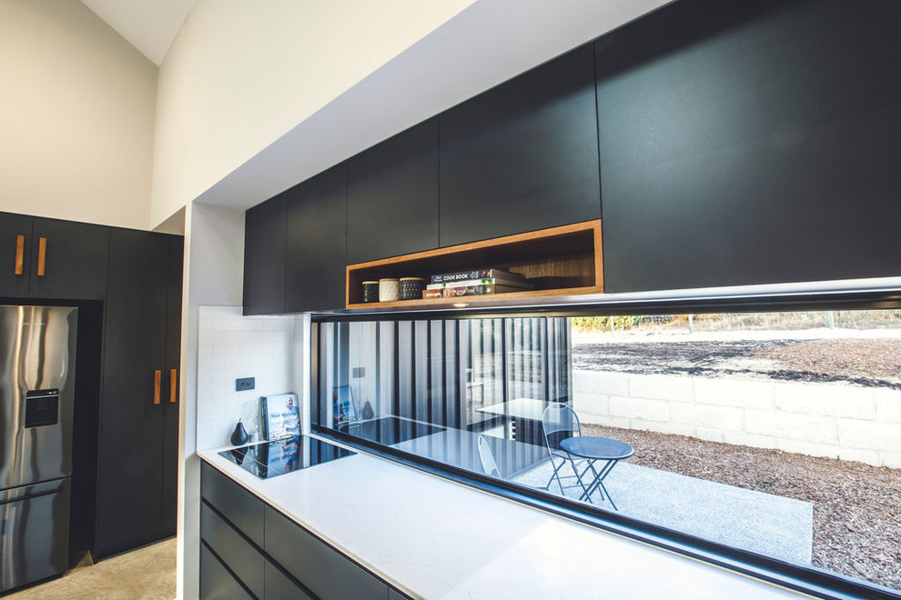 Esempio di una cucina minimalista con lavello a vasca singola, ante nere, top in quarzo composito, paraspruzzi con lastra di vetro, elettrodomestici neri, pavimento in cemento e top bianco