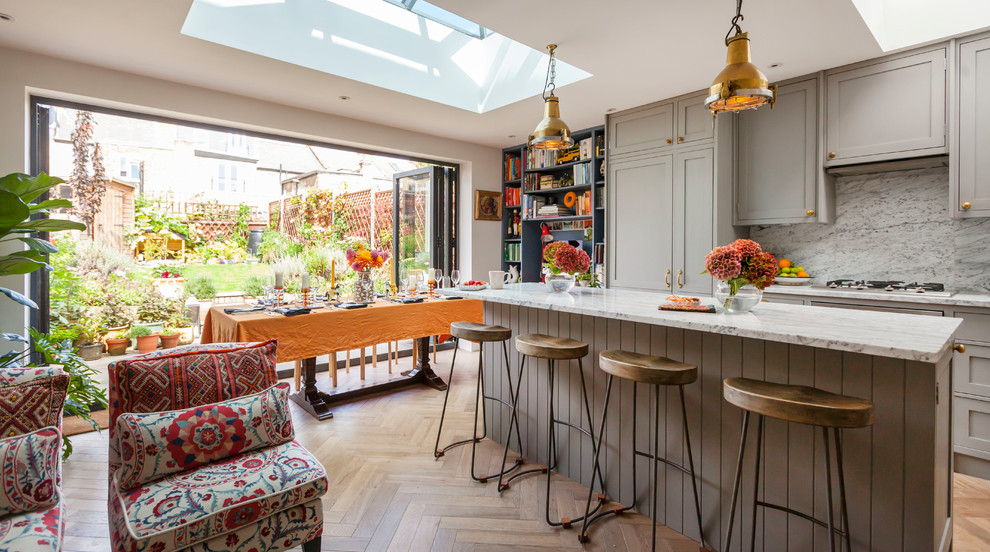 Medium sized bohemian single-wall kitchen in London with shaker cabinets, grey cabinets, marble worktops, white splashback, an island and beige floors.