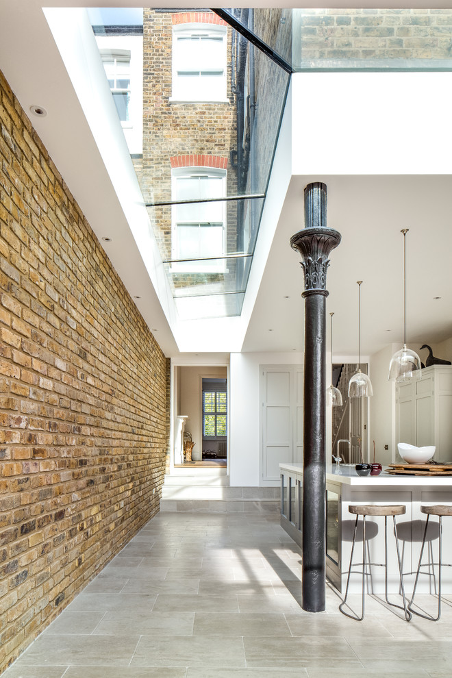 Example of a mid-sized transitional limestone floor eat-in kitchen design in London with an integrated sink, shaker cabinets, gray cabinets, solid surface countertops, stainless steel appliances and an island