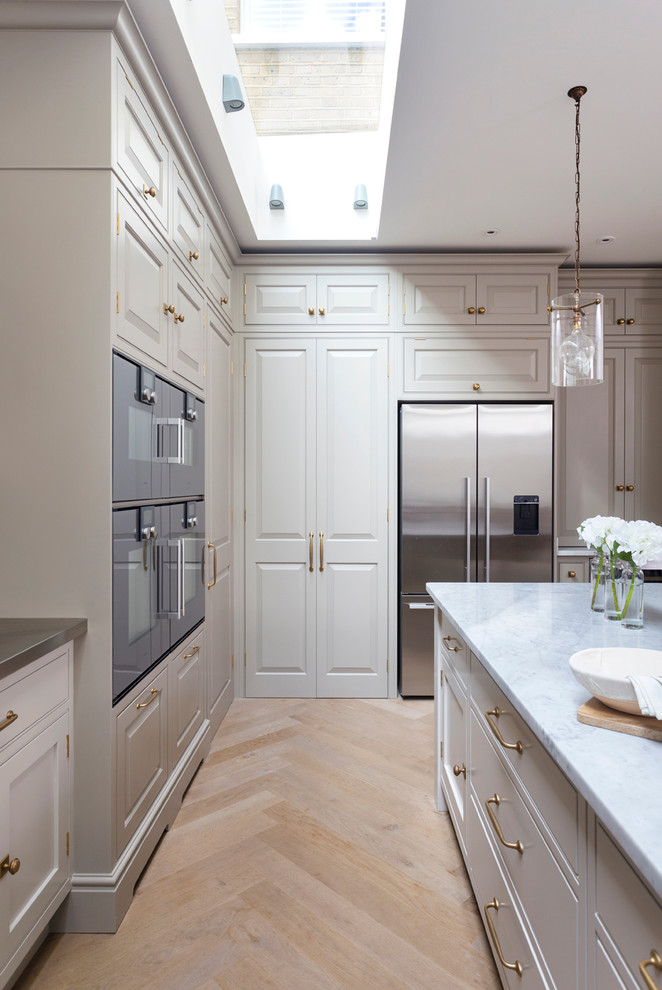 Foto de cocina clásica grande con armarios con paneles lisos y suelo de madera clara