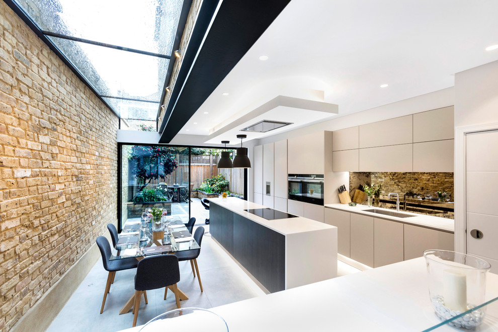 Bild på ett mellanstort funkis vit linjärt vitt kök och matrum, med en undermonterad diskho, släta luckor, beige skåp, bänkskiva i kvartsit, spegel som stänkskydd, rostfria vitvaror, en köksö och grått golv