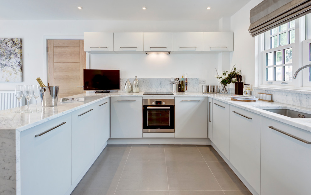 Moderne Küche mit Unterbauwaschbecken, weißen Schränken und Halbinsel in London