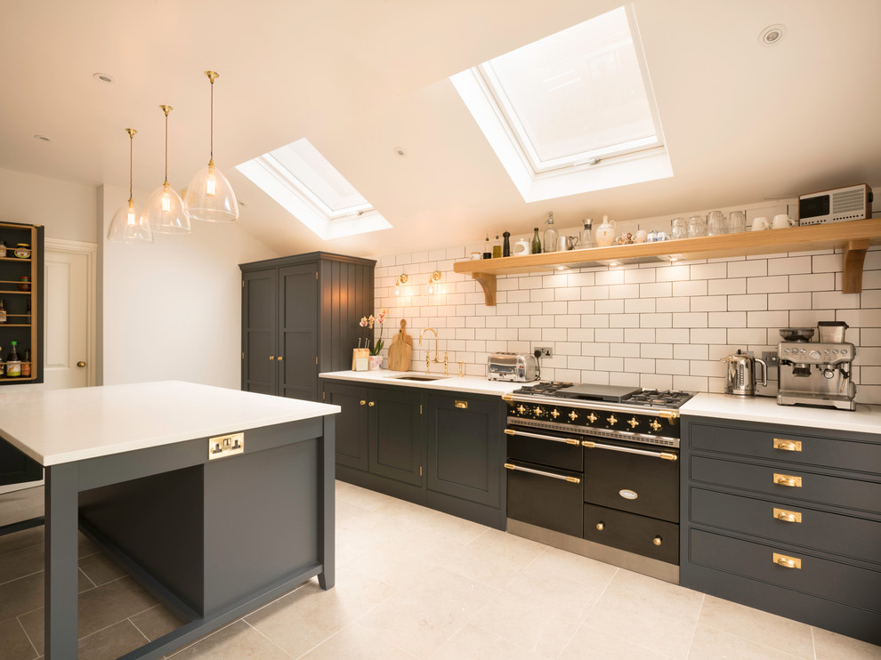 Inspiration for a transitional single-wall kitchen remodel in London with an undermount sink, shaker cabinets, gray cabinets, white backsplash, subway tile backsplash, black appliances and an island