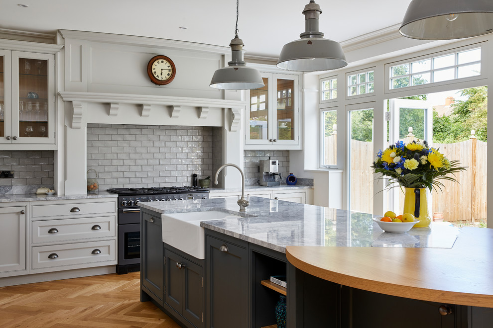 Klassisk inredning av ett stort grå grått kök, med en rustik diskho, skåp i shakerstil, grå skåp, granitbänkskiva, grått stänkskydd, stänkskydd i keramik, färgglada vitvaror, mellanmörkt trägolv, en köksö och brunt golv