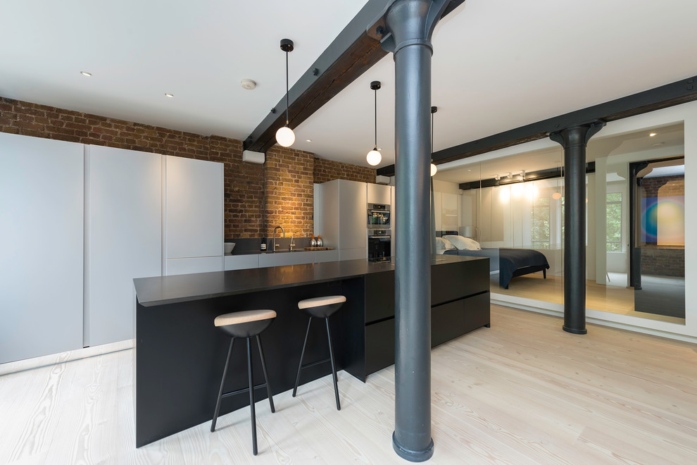 Einzeilige, Große Moderne Wohnküche mit flächenbündigen Schrankfronten, grauen Schränken, hellem Holzboden und Kücheninsel in London