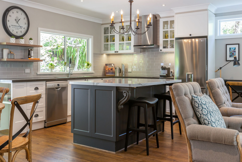 Design ideas for a large classic l-shaped open plan kitchen in Other with a double-bowl sink, shaker cabinets, white cabinets, engineered stone countertops, grey splashback, metro tiled splashback, stainless steel appliances, vinyl flooring, an island, brown floors and grey worktops.