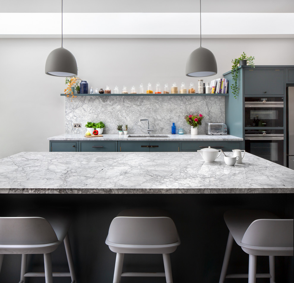 Inspiration for a scandinavian kitchen in London with a submerged sink, flat-panel cabinets, blue cabinets, grey splashback, stone slab splashback, an island and grey worktops.