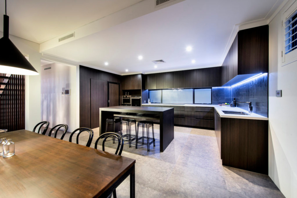 This is an example of a large urban galley kitchen/diner in Perth with a double-bowl sink, flat-panel cabinets, dark wood cabinets, engineered stone countertops, black splashback, ceramic splashback, stainless steel appliances, cement flooring, an island, grey floors and white worktops.