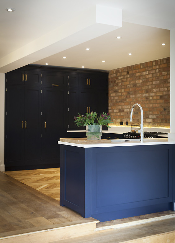 Photo of a medium sized urban l-shaped open plan kitchen in Other with a submerged sink, shaker cabinets, black cabinets, composite countertops, brick splashback, black appliances, light hardwood flooring, no island, beige floors and white worktops.
