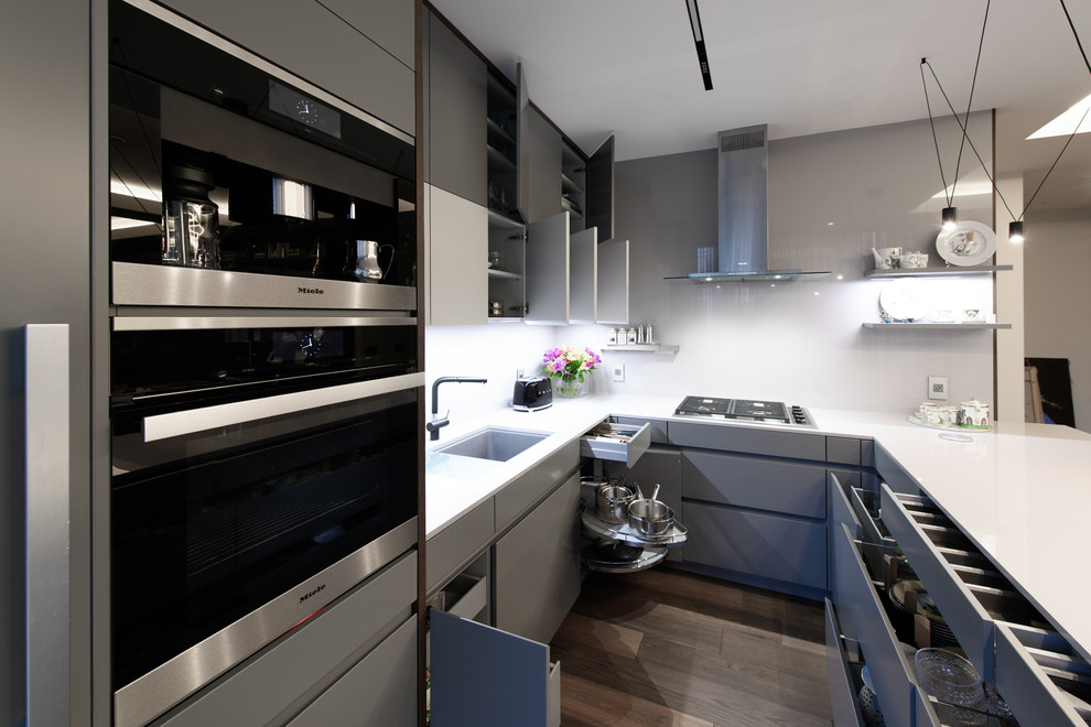 Idéer för ett mellanstort modernt vit u-kök, med en undermonterad diskho, släta luckor, grå skåp, vitt stänkskydd, rostfria vitvaror, en halv köksö och brunt golv
