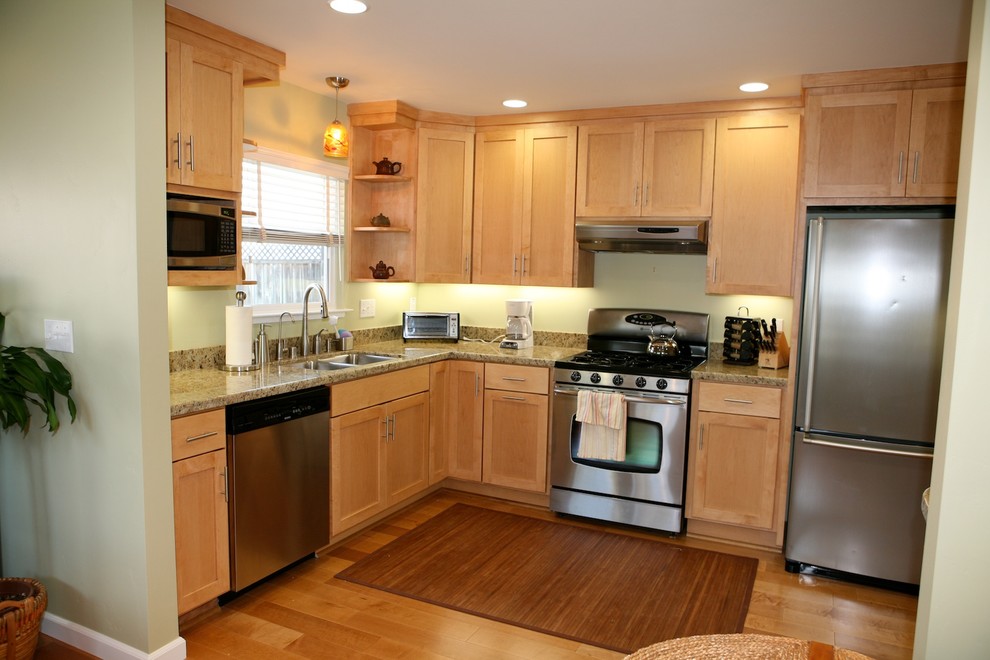 Modern inredning av ett mellanstort kök, med en undermonterad diskho, skåp i shakerstil, skåp i ljust trä, granitbänkskiva, grönt stänkskydd, stänkskydd i sten, rostfria vitvaror och mellanmörkt trägolv
