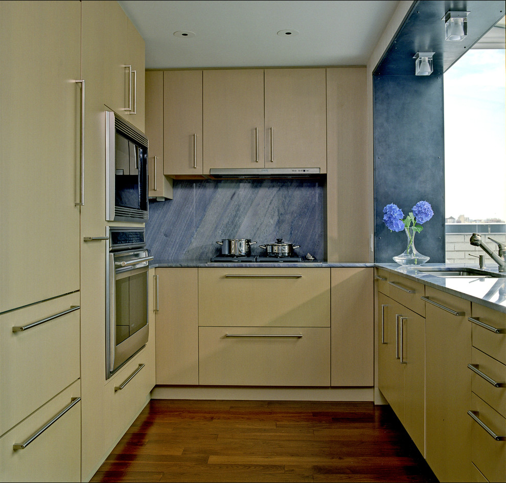 Modern inredning av ett stort blå blått kök, med en nedsänkt diskho, släta luckor, beige skåp, bänkskiva i kvartsit, blått stänkskydd, stänkskydd i sten, rostfria vitvaror, mörkt trägolv, en halv köksö och brunt golv