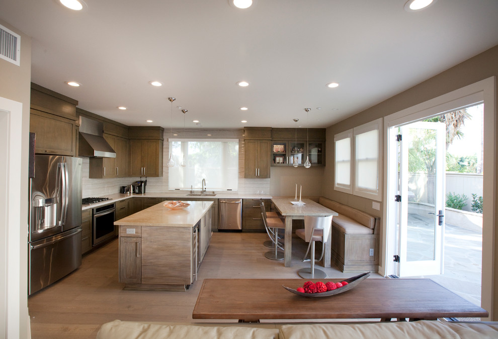 Diseño de cocina moderna de tamaño medio con fregadero de doble seno, armarios estilo shaker, salpicadero de losas de piedra, electrodomésticos de acero inoxidable, suelo de madera clara, una isla, puertas de armario de madera clara, encimera de piedra caliza, salpicadero verde, suelo beige y encimeras beige