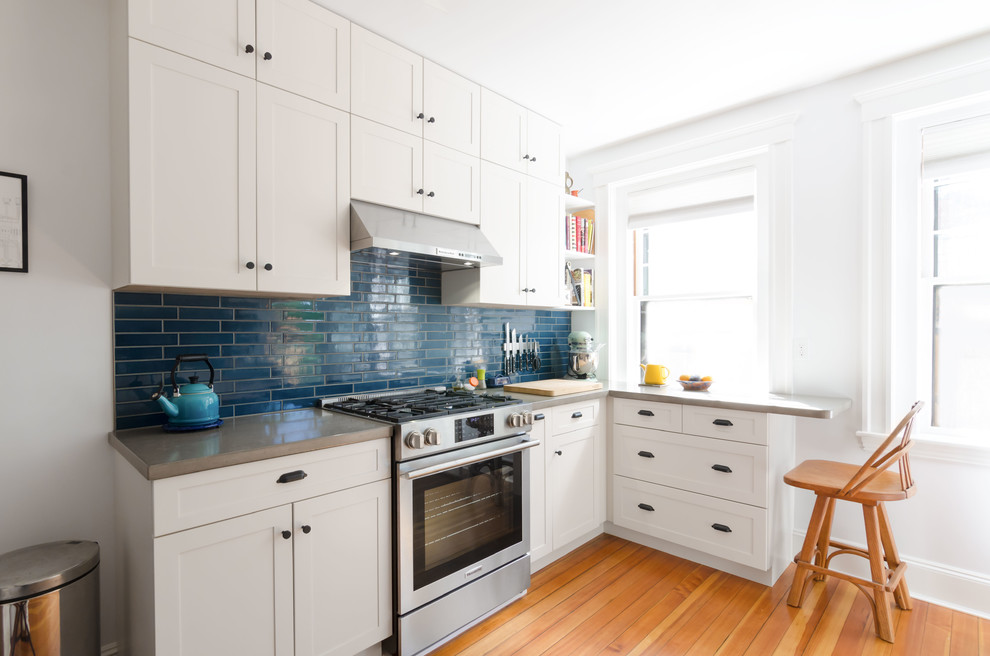 Mid-sized eclectic u-shaped light wood floor and brown floor enclosed kitchen photo in Boston with an undermount sink, recessed-panel cabinets, white cabinets, concrete countertops, blue backsplash, subway tile backsplash, white appliances and no island
