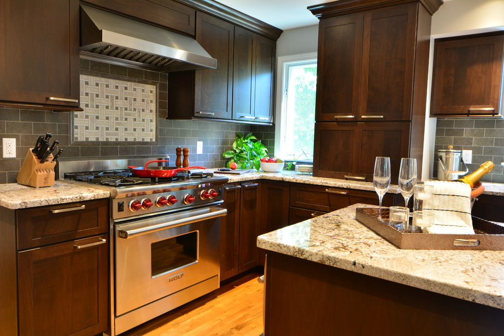 Example of a transitional l-shaped eat-in kitchen design in Boston with a farmhouse sink, shaker cabinets, dark wood cabinets, granite countertops, brown backsplash, subway tile backsplash and stainless steel appliances