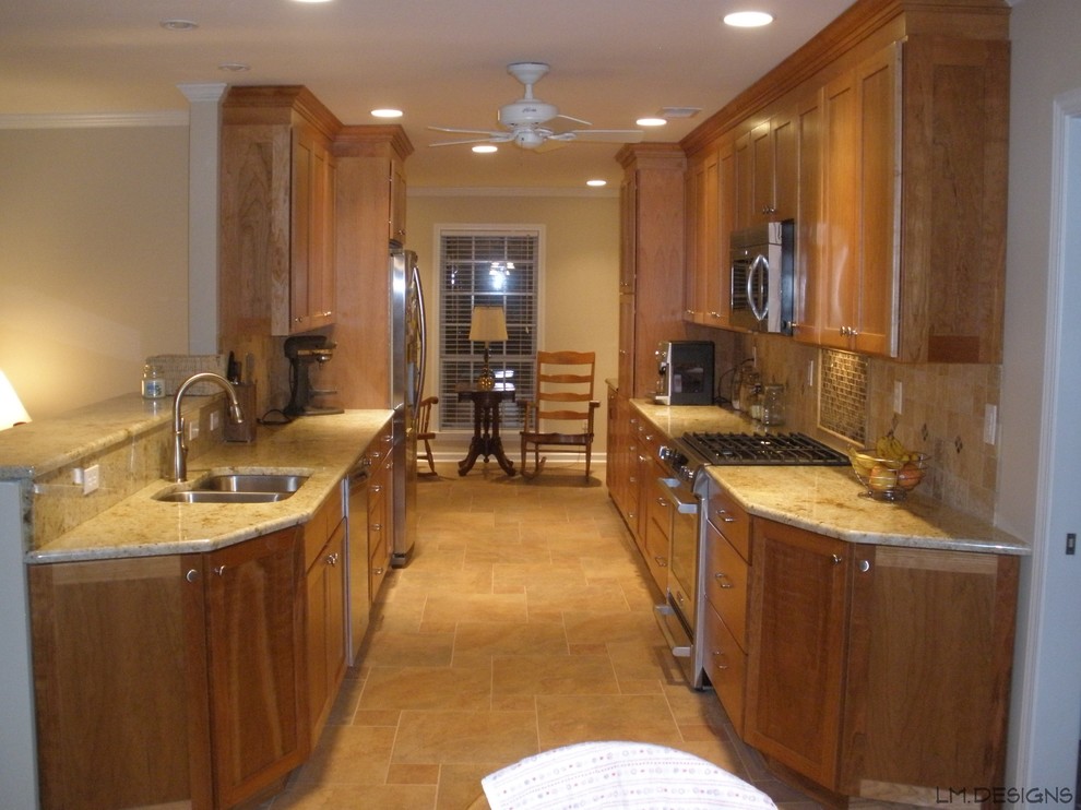 Cette photo montre une cuisine américaine parallèle chic en bois clair avec un évier encastré, un placard à porte shaker, un plan de travail en granite, un électroménager en acier inoxydable et aucun îlot.