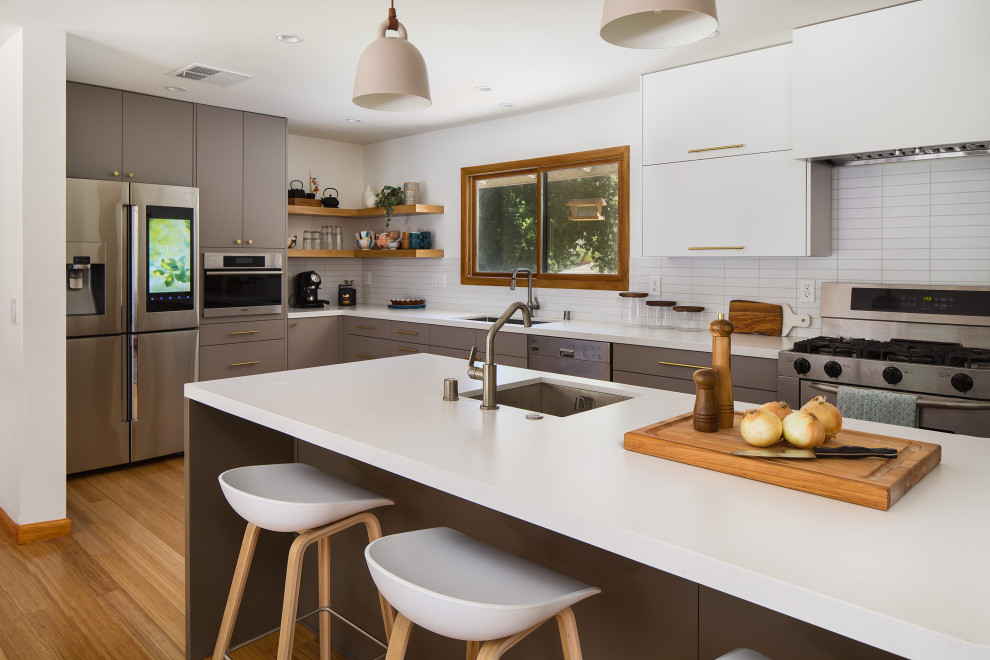 Expansive scandi galley kitchen/diner in Los Angeles with a submerged sink, flat-panel cabinets, grey cabinets, engineered stone countertops, white splashback, metro tiled splashback, stainless steel appliances, bamboo flooring, a breakfast bar, yellow floors and white worktops.