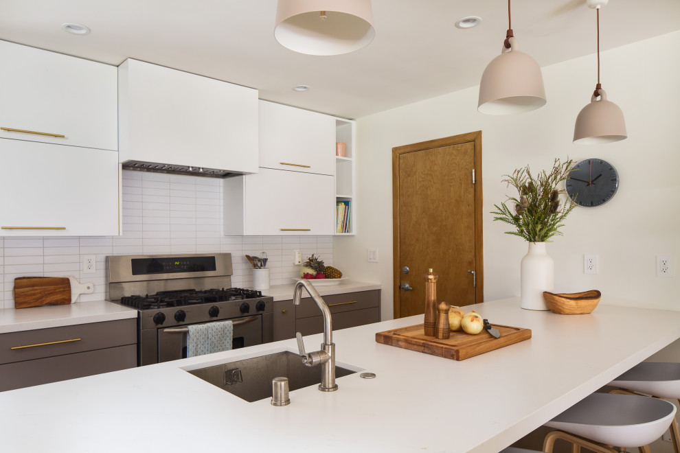 Inspiration for an expansive scandinavian galley kitchen/diner in Los Angeles with a submerged sink, flat-panel cabinets, grey cabinets, engineered stone countertops, white splashback, metro tiled splashback, stainless steel appliances, bamboo flooring, a breakfast bar, yellow floors and white worktops.