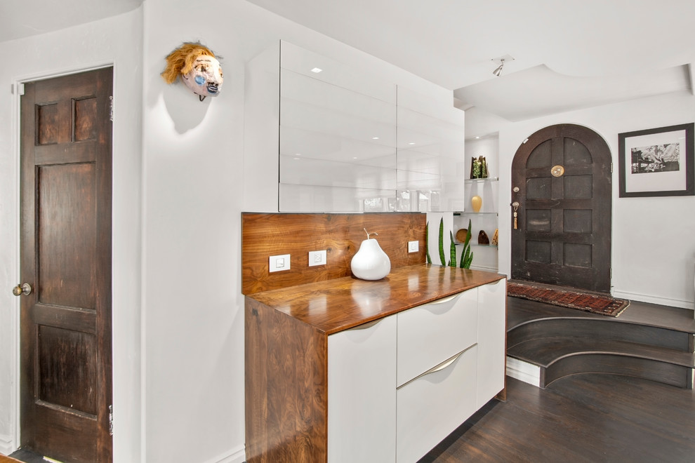 Foto di una grande cucina minimal con ante lisce, ante bianche, top in legno, paraspruzzi marrone, elettrodomestici bianchi, pavimento marrone e top marrone