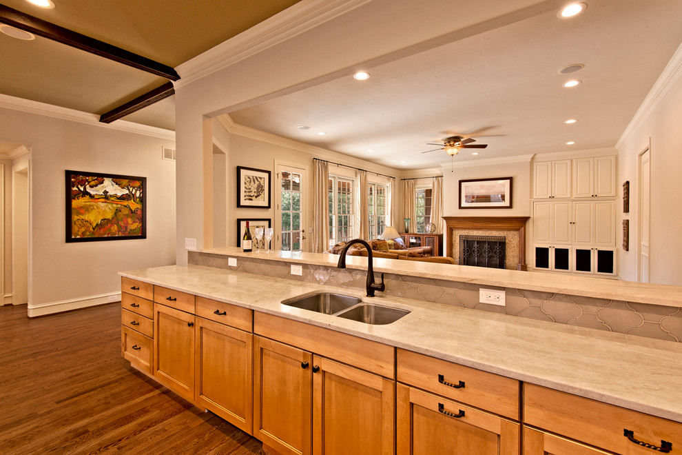 Exempel på ett klassiskt kök, med en undermonterad diskho, luckor med profilerade fronter, skåp i ljust trä, granitbänkskiva, beige stänkskydd, stänkskydd i porslinskakel, rostfria vitvaror, mellanmörkt trägolv och en köksö
