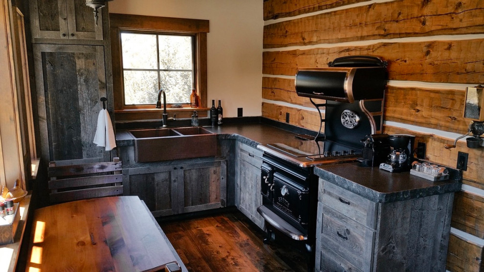 Design ideas for a small rustic l-shaped kitchen/diner in Other with a belfast sink, shaker cabinets, distressed cabinets, granite worktops, black appliances, dark hardwood flooring and no island.