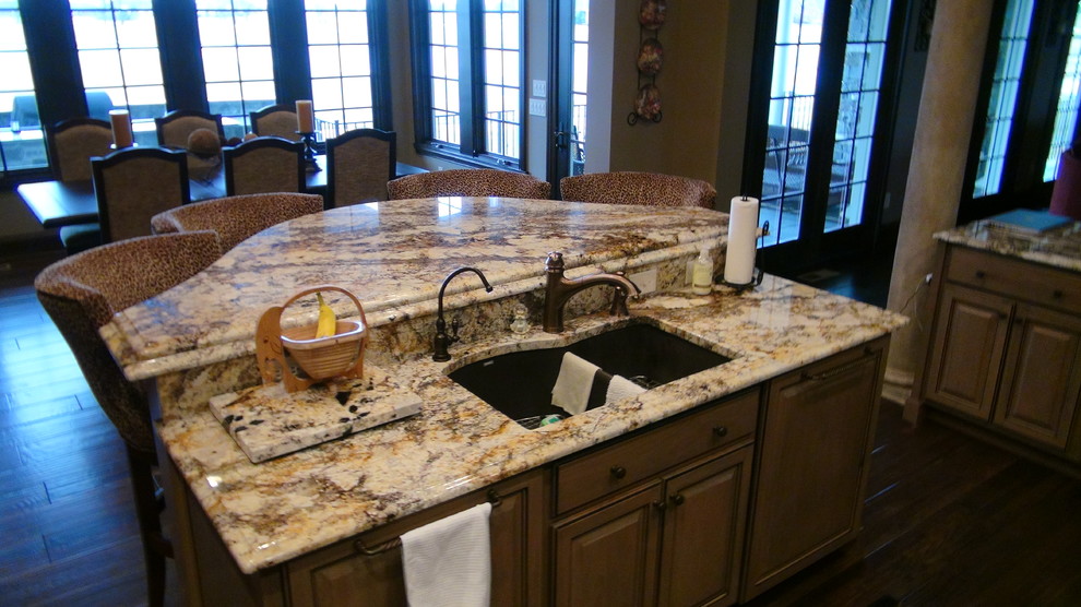 Inspiration for a mid-sized timeless medium tone wood floor kitchen remodel in Indianapolis with an undermount sink, raised-panel cabinets, medium tone wood cabinets, granite countertops, gray backsplash, stone tile backsplash and paneled appliances