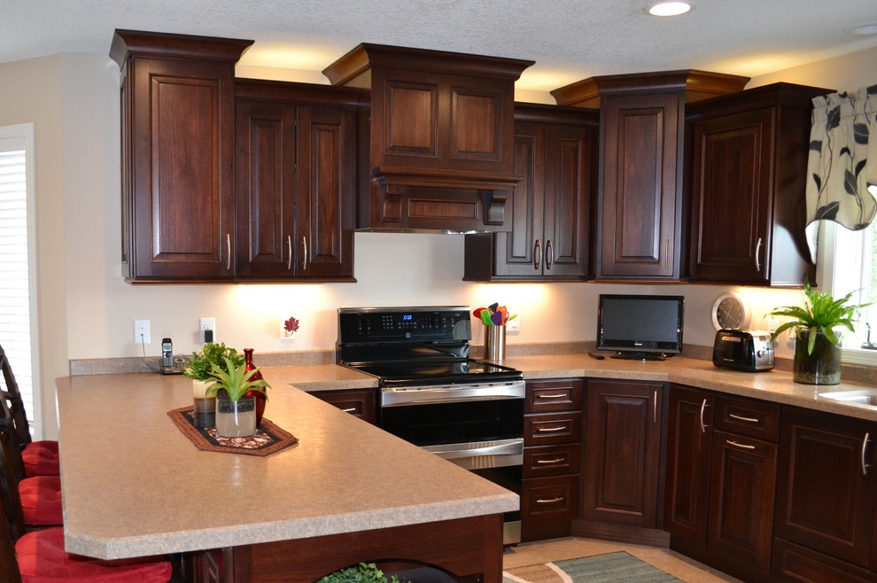 Klassisk inredning av ett mellanstort kök, med en undermonterad diskho, luckor med upphöjd panel, skåp i mörkt trä, laminatbänkskiva, rostfria vitvaror och en halv köksö