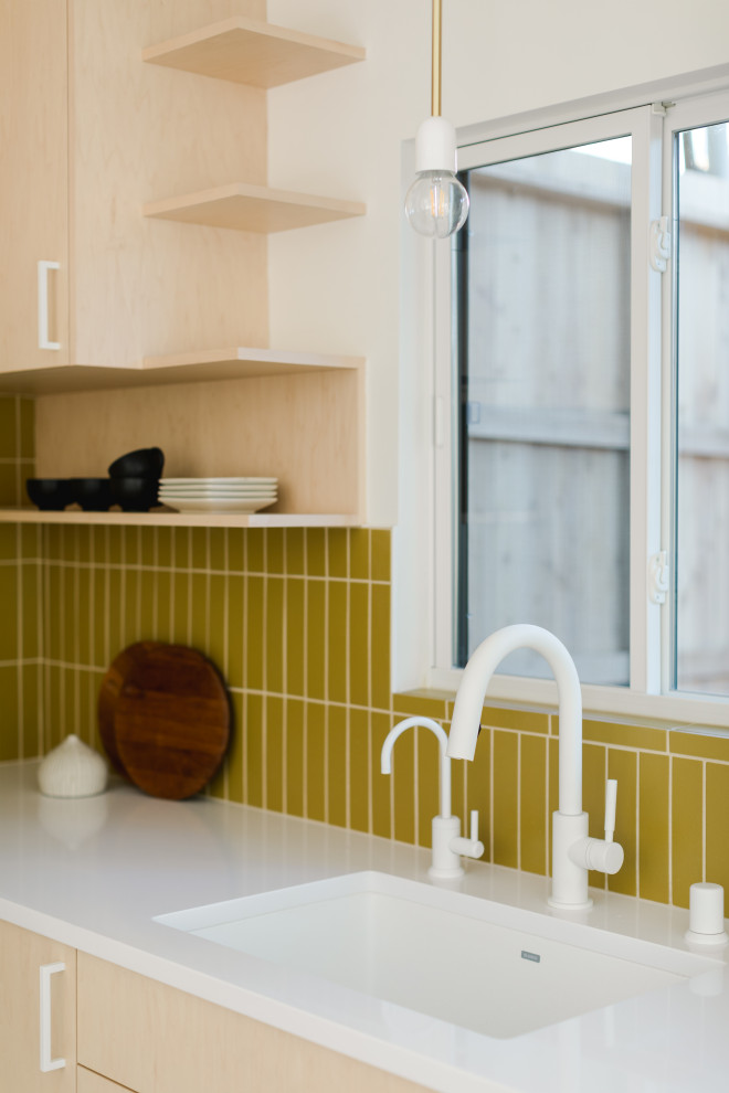 This is an example of a small scandinavian l-shaped enclosed kitchen in Los Angeles with beige cabinets, yellow splashback, ceramic splashback, white appliances, concrete flooring, no island, multi-coloured floors and white worktops.