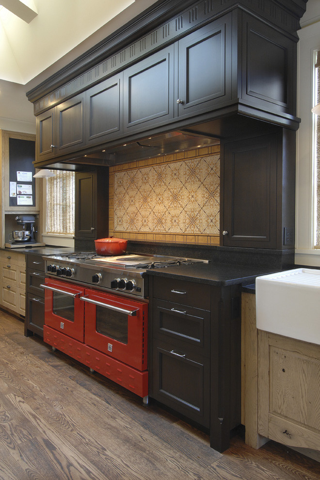 Diseño de cocina tradicional con electrodomésticos de colores, fregadero sobremueble, armarios con paneles empotrados, puertas de armario negras y salpicadero multicolor