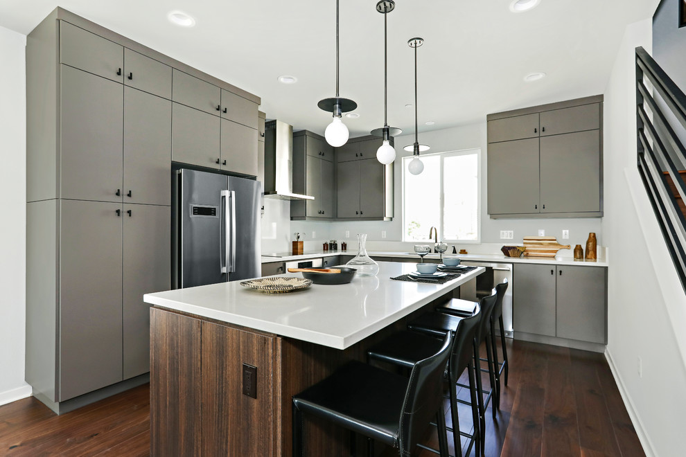 Esempio di una cucina design con ante lisce, elettrodomestici in acciaio inossidabile, ante grigie, parquet scuro, pavimento marrone e top bianco
