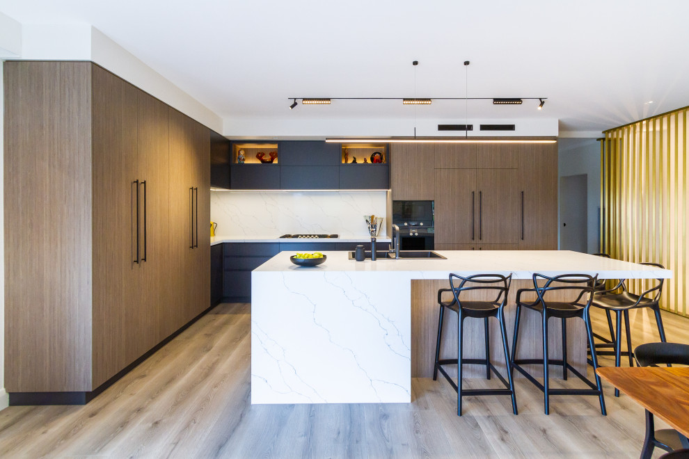 Eat-in kitchen - mid-sized modern l-shaped light wood floor and beige floor eat-in kitchen idea in Melbourne with a double-bowl sink, flat-panel cabinets, medium tone wood cabinets, quartz countertops, white backsplash, stone slab backsplash, black appliances, an island and white countertops