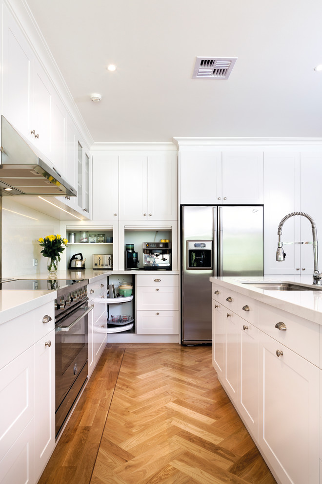 Offene Klassische Küche in L-Form mit Schrankfronten im Shaker-Stil, weißen Schränken, Küchenrückwand in Weiß und Küchengeräten aus Edelstahl in Melbourne