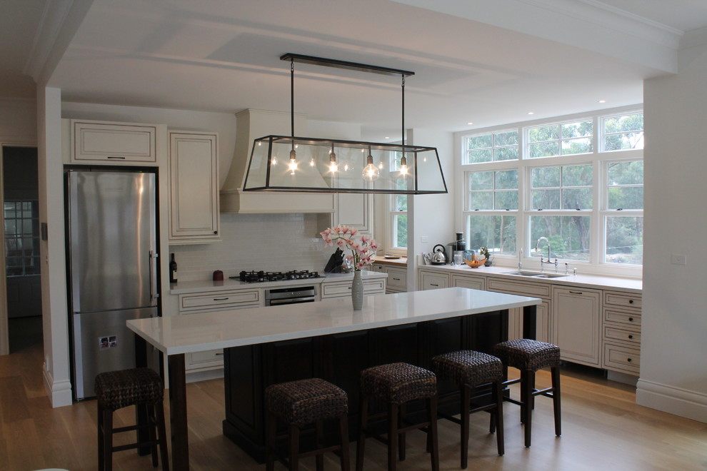 メルボルンにある高級な広いトランジショナルスタイルのおしゃれなアイランドキッチン (ダブルシンク、黄色いキッチンパネル、シルバーの調理設備) の写真