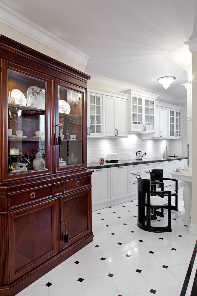 Inredning av ett klassiskt kök, med en undermonterad diskho, vita skåp, granitbänkskiva, vitt stänkskydd, stänkskydd i porslinskakel och rostfria vitvaror