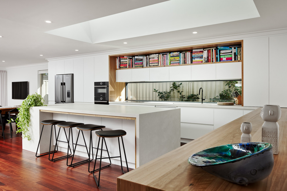 Design ideas for a large contemporary l-shaped kitchen/diner in Perth with a submerged sink, flat-panel cabinets, white cabinets, engineered stone countertops, window splashback, black appliances, dark hardwood flooring, an island, brown floors and white worktops.