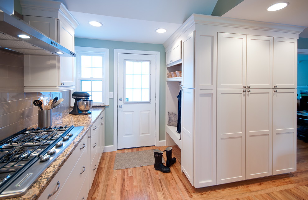 Open concept kitchen - large traditional single-wall light wood floor open concept kitchen idea in Providence with a peninsula, shaker cabinets, white cabinets, granite countertops, brown backsplash, subway tile backsplash, stainless steel appliances and an undermount sink