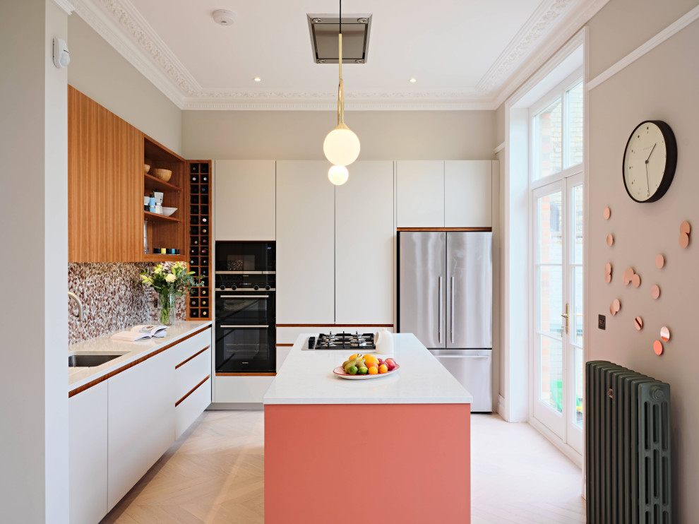 Medium sized eclectic l-shaped kitchen/diner in London with a submerged sink, flat-panel cabinets, white cabinets, composite countertops, multi-coloured splashback, mosaic tiled splashback, black appliances, light hardwood flooring, an island, grey floors and white worktops.