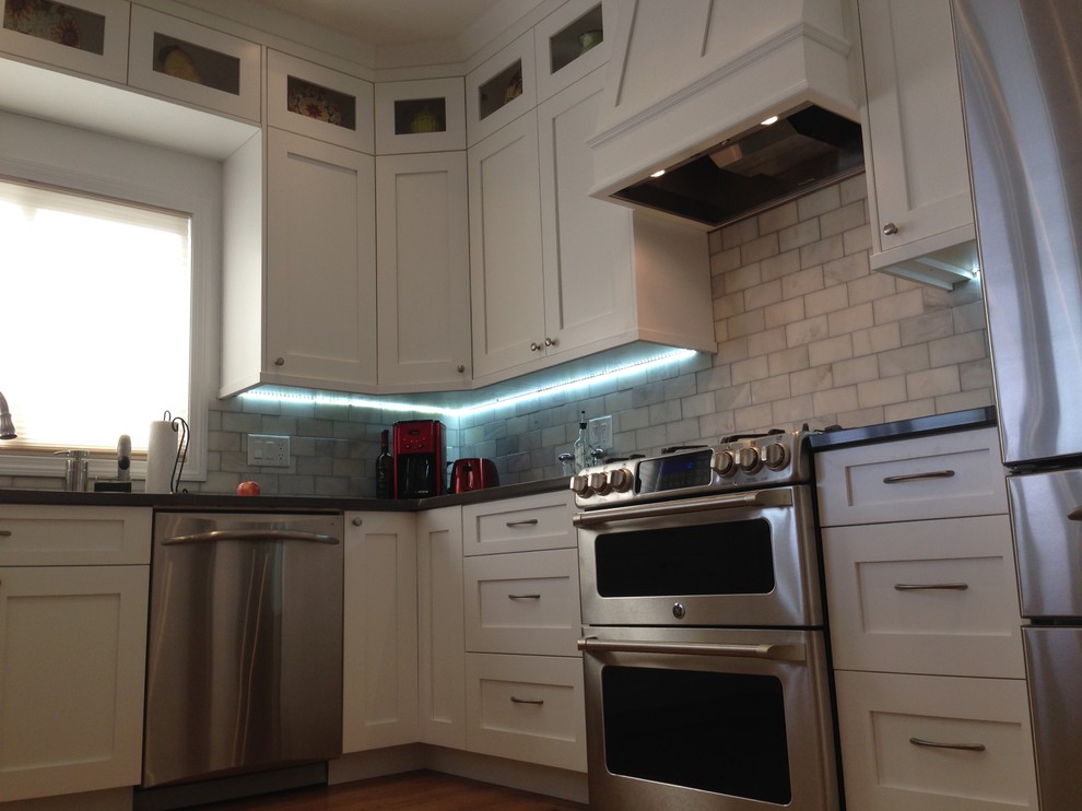 Example of a large classic u-shaped medium tone wood floor eat-in kitchen design in Denver with an undermount sink, shaker cabinets, white cabinets, quartz countertops, white backsplash, subway tile backsplash, stainless steel appliances and a peninsula
