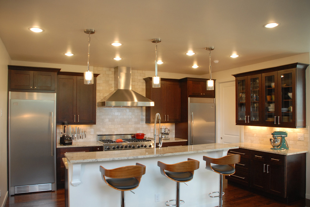 Bild på ett litet eklektiskt kök, med en dubbel diskho, luckor med infälld panel, skåp i mörkt trä, granitbänkskiva, beige stänkskydd, stänkskydd i stenkakel, rostfria vitvaror, mellanmörkt trägolv och en köksö