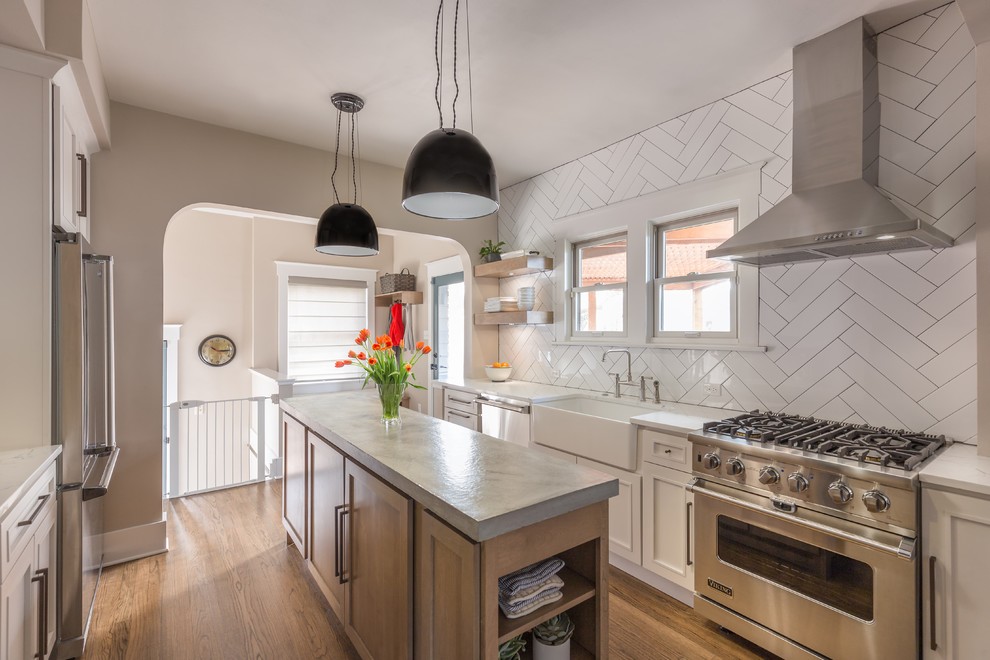 Transitional galley medium tone wood floor and brown floor eat-in kitchen photo in Denver with a farmhouse sink, shaker cabinets, white cabinets, concrete countertops, white backsplash, subway tile backsplash, stainless steel appliances and an island