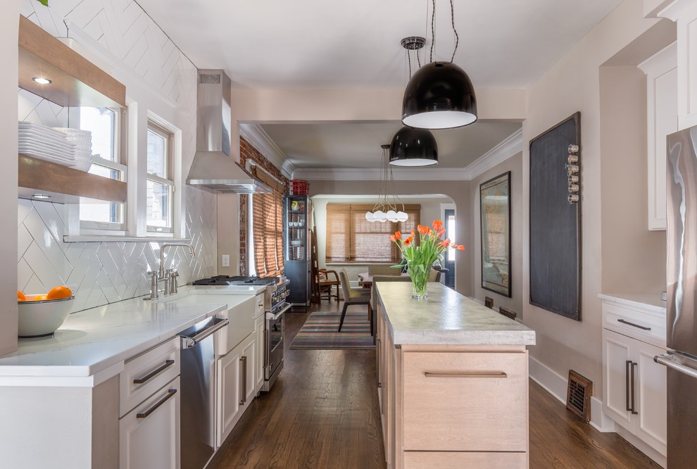 Example of a transitional galley medium tone wood floor and brown floor eat-in kitchen design in Denver with a farmhouse sink, shaker cabinets, white cabinets, concrete countertops, white backsplash, subway tile backsplash, stainless steel appliances and an island