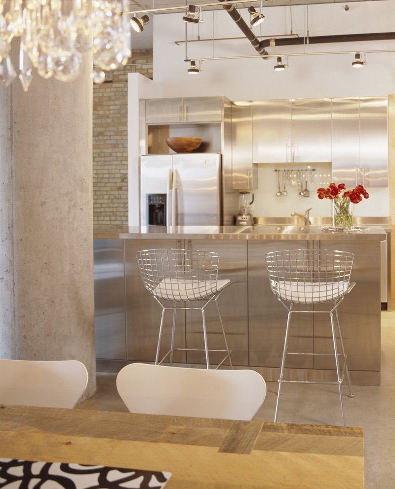 Example of a trendy kitchen design in Minneapolis with stainless steel cabinets, stainless steel countertops, flat-panel cabinets and stainless steel appliances