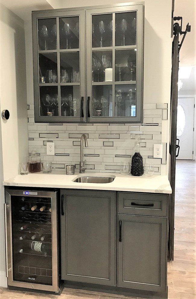 Large transitional l-shaped porcelain tile and brown floor eat-in kitchen photo in Boston with a farmhouse sink, shaker cabinets, gray cabinets, quartz countertops, metallic backsplash, glass tile backsplash, stainless steel appliances and an island