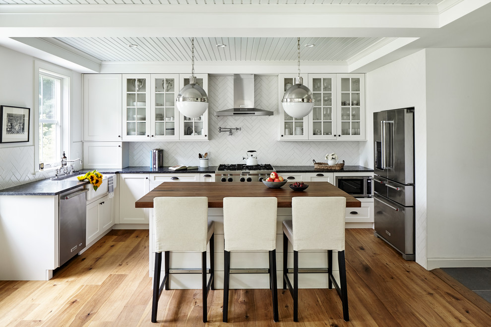 Exempel på ett mellanstort lantligt l-kök, med en rustik diskho, vita skåp, granitbänkskiva, vitt stänkskydd, stänkskydd i keramik, rostfria vitvaror, ljust trägolv, en köksö och luckor med glaspanel
