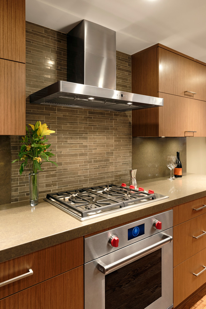 Example of a mid-sized trendy u-shaped medium tone wood floor eat-in kitchen design in DC Metro with an integrated sink, flat-panel cabinets, medium tone wood cabinets, quartz countertops, stone tile backsplash, paneled appliances, an island and gray backsplash