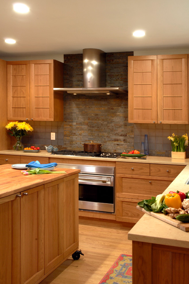 Inredning av ett amerikanskt mellanstort kök, med en undermonterad diskho, luckor med lamellpanel, skåp i mellenmörkt trä, träbänkskiva, blått stänkskydd, stänkskydd i keramik, rostfria vitvaror, ljust trägolv och en köksö