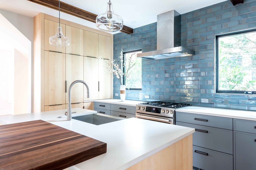 Inspiration for a medium sized contemporary u-shaped kitchen/diner in DC Metro with a belfast sink, flat-panel cabinets, blue cabinets, concrete worktops, blue splashback, metro tiled splashback, stainless steel appliances, light hardwood flooring, an island, beige floors and white worktops.