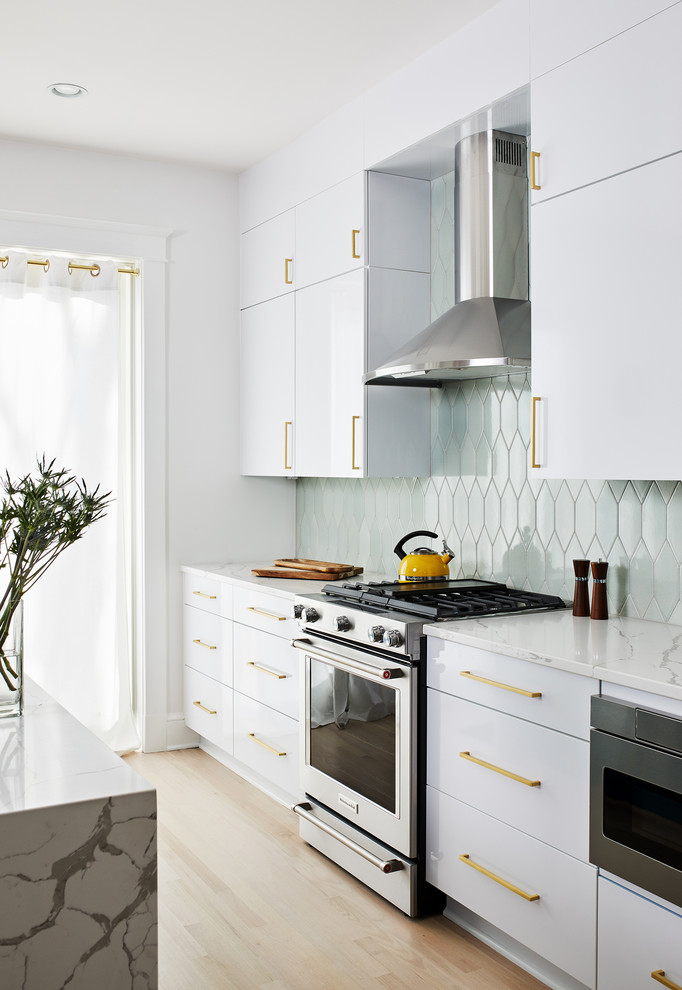 ワシントンD.C.にあるコンテンポラリースタイルのおしゃれなアイランドキッチン (フラットパネル扉のキャビネット、ターコイズのキャビネット、緑のキッチンパネル、シルバーの調理設備、淡色無垢フローリング、白いキッチンカウンター) の写真
